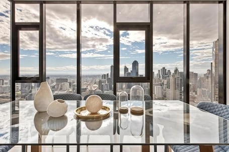 A high-rise room with a glass table, decorative items, and a city view.