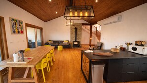 Una sala de estar acogedora con chimenea, muebles de madera y un comedor con sillas amarillas.