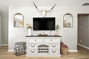 A room with a white vanity, a mounted television, and two wall-mounted mirrors. - 3BD Retreat| 5 Mins to Downtown! (Abilene)