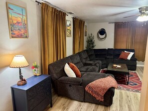 Un saló amb un sofà modular, una taula petita, una làmpada i una planta decorativa.