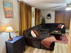 Ein Wohnzimmer mit einem dunkelgrauen Sofa, einem Couchtisch, einer Lampe und einer Zimmerpflanze.