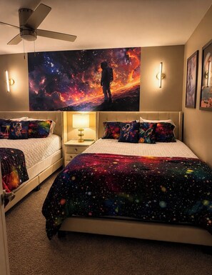 A bedroom with two beds, a ceiling fan, wall-mounted lights, and a large space-themed tapestry. - Kaleidoscope House (Abilene)