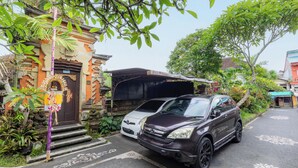 Un edificio tradizionale con un portico, un'auto parcheggiata e un pilastro decorato con un'esposizione floreale.