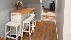 Une cuisine moderne avec un plan de travail en bois, des tabourets de bar blancs et un four encastré.