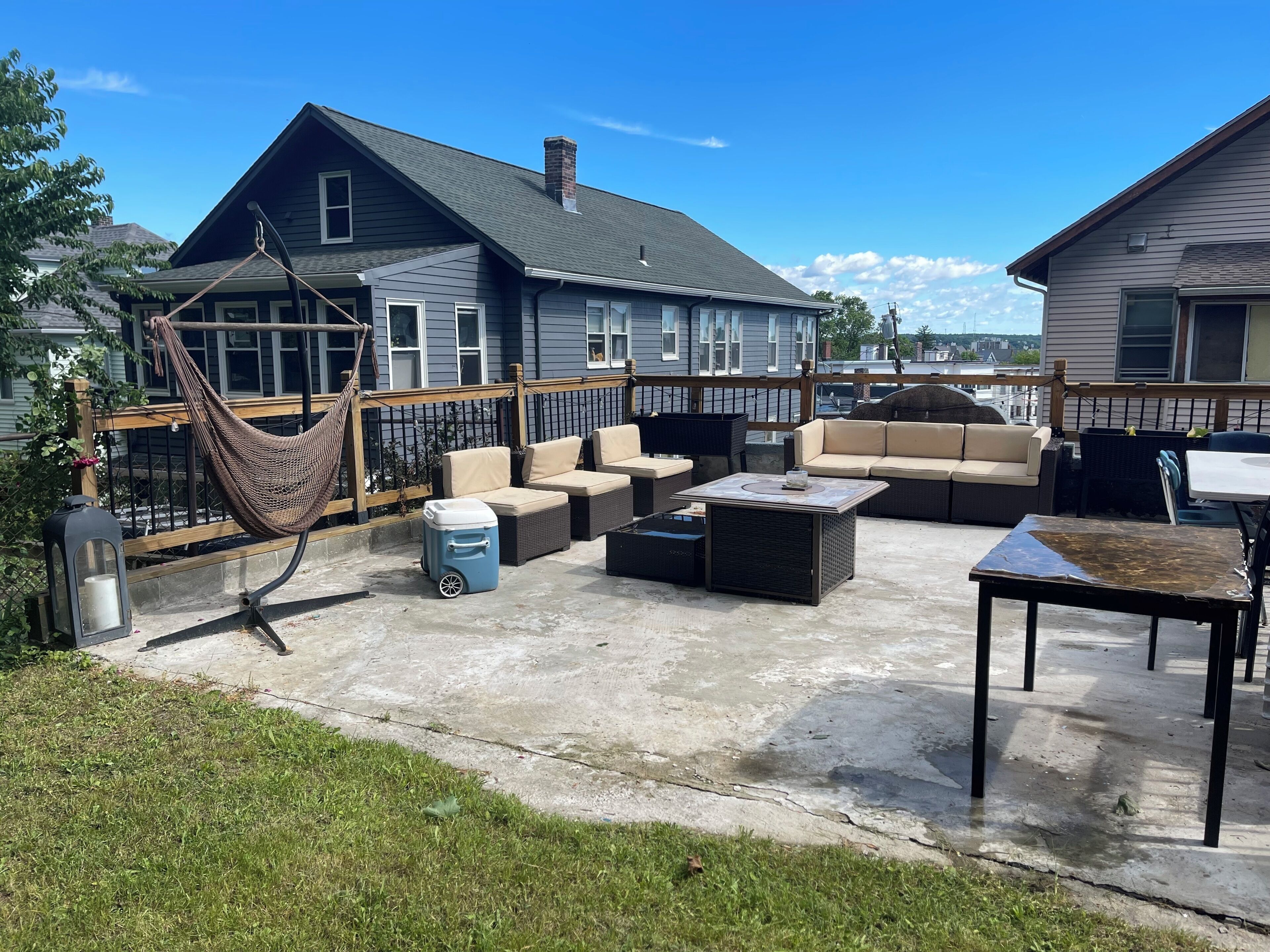 A patio with outdoor furniture, a hammock, and a cooler.