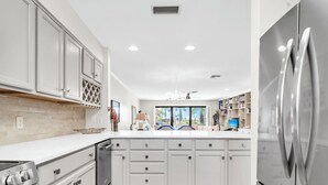 Una cocina moderna con armarios blancos, electrodomésticos de acero inoxidable y suelo de madera.
