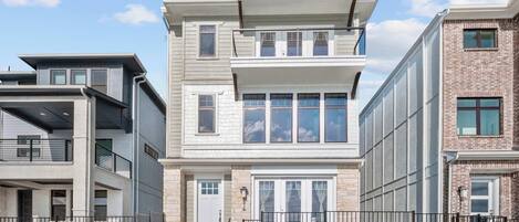 A modern multi-story residential building with a flat roof, large windows, and a brick facade.