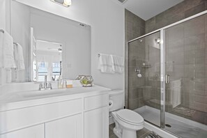 A modern bathroom with a white vanity, a glass shower enclosure, and a large mirror. - Luxury 3 Bedroom WaterfrontHome Near DAL (Rowlett)
