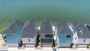 A row of three-story buildings with flat roofs, positioned along a waterfront.