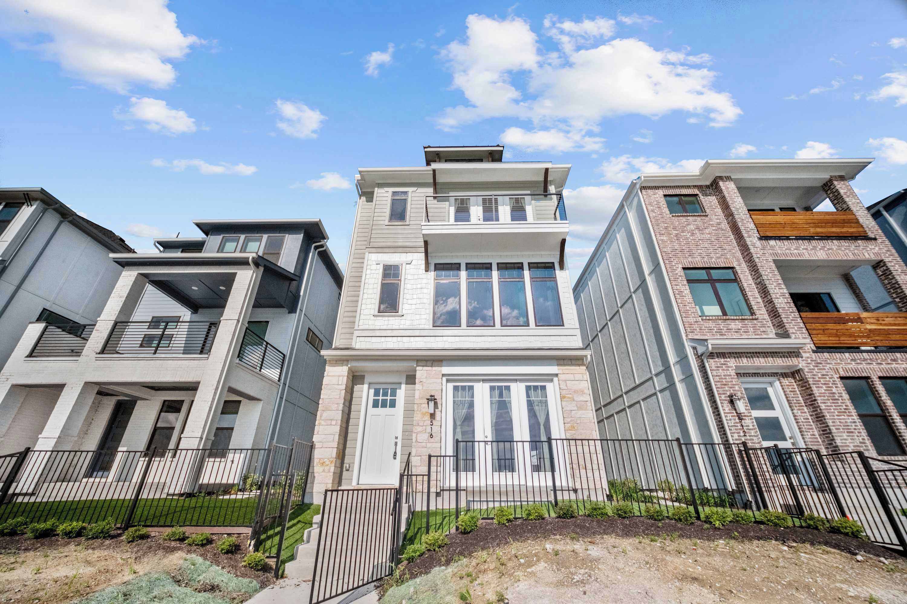 A modern multi-story residential building with a flat roof, large windows, and a brick facade.
