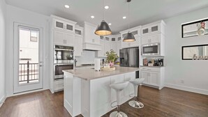 A modern kitchen with white cabinetry, stainless steel appliances, and a central island with bar stools.