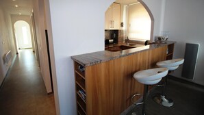 A modern kitchen with a wooden island, a marble countertop, and a built-in sink. - CALA FONDA Apartment in Santa Margarita Roses (ROSES)