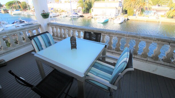 A terrace with a table and chairs, overlooking a marina with boats and buildings. - CALA FONDA Apartment in Santa Margarita Roses (ROSES)