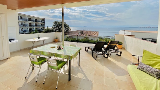 A balcony with a table and chairs, a sofa, and a view of the sea. - CENTRAL Apartment Roses near the beach with sea view (Roses)