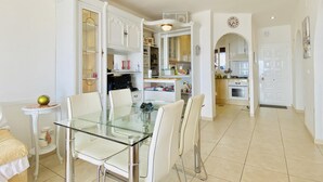 A modern kitchen with white cabinetry, a glass dining table, and a separate dining area. - CENTRAL Apartment Roses near the beach with sea view (Roses)