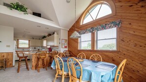 Ein gemütliches Blockhaus-Interieur mit Essbereich, Küche und einem großen Fenster mit Jalousien.