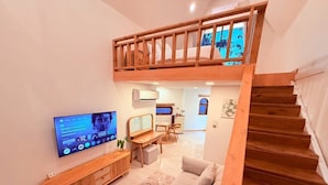 A modern living room with a wooden staircase, a TV mounted on the wall, and a cozy seating area. - Lanta Forest Resort&Villas  (Ko Lanta)