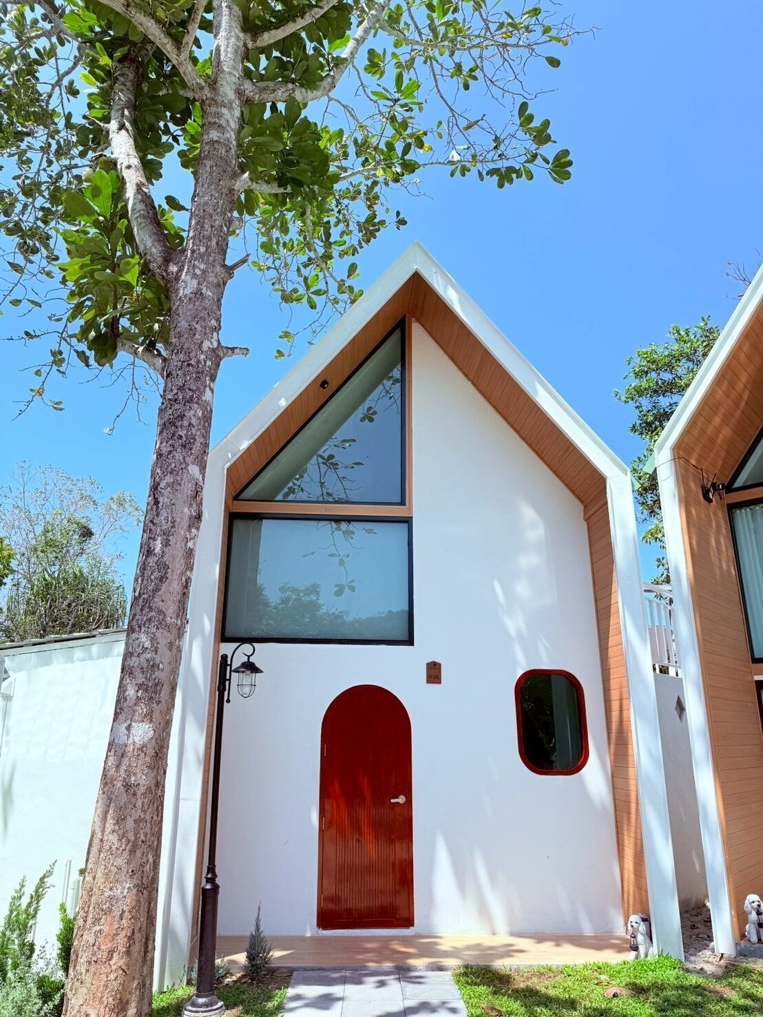 A modern house with a white exterior, a red door, and a large window.