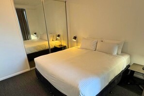 Ein Hotelzimmer mit einem großen Bett, einem Nachttisch mit Lampe und einem Spiegel an der Wand.