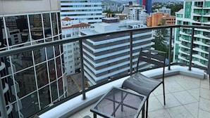 A balcony with a view of city buildings, a table, and a chair. - Dreamy Cityside 2BR Haven Brisbane Central (Brisbane City)