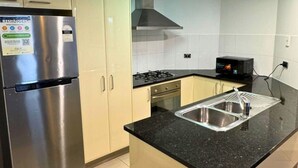 A kitchen with a stainless steel refrigerator, a microwave, a stove, and a sink. - Dreamy Cityside 2BR Haven Brisbane Central (Brisbane City)
