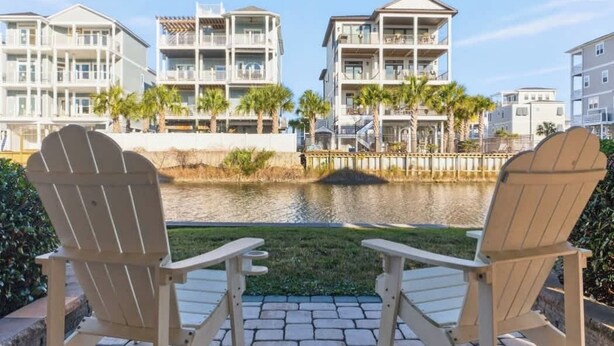 Vista sull'acqua con due poltrone Adirondack, un piccolo stagno e una fila di edifici a più piani con balconi.