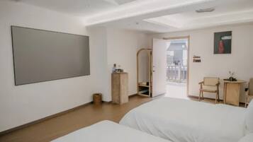 Habitación de hotel con dos camas, un espejo grande, una mesita y una silla.
