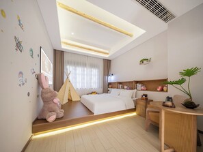 Ein modernes Hotelzimmer mit Bett, Sitzecke, einem kleinen Tisch und einem Fenster mit Vorhängen.