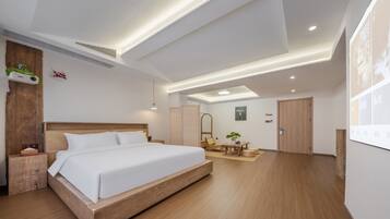 Una habitación de hotel moderna con una cama grande, suelo de madera, un escritorio y una zona de estar.