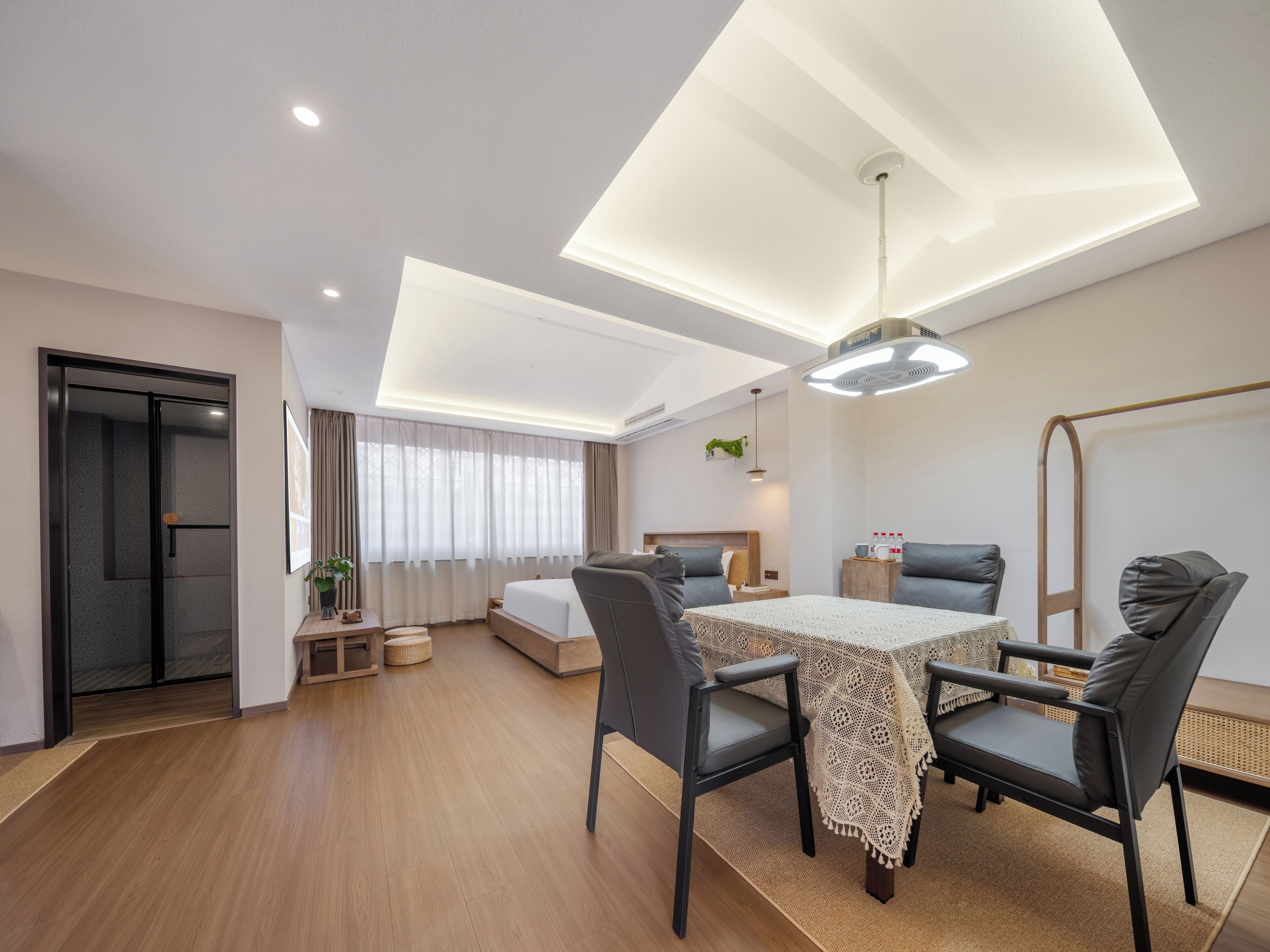 Habitació d'hotel moderna amb zona de menjador, un llit, un sofà i una làmpada al sostre.
