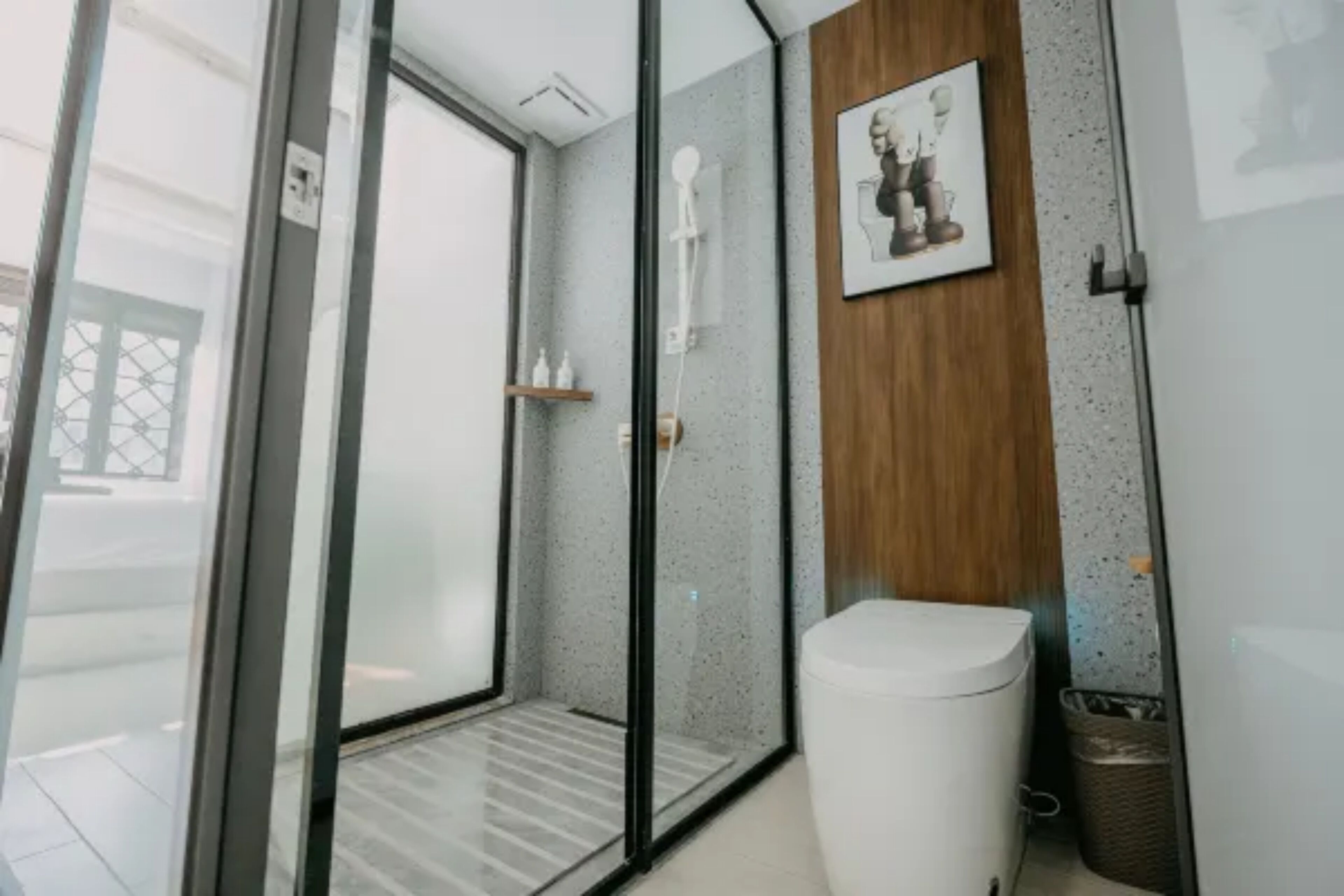Un baño moderno con cabina de ducha de vidrio, inodoro y pared de paneles de madera.