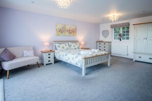 A bedroom with a bed, nightstands, a dresser, a vanity, and a window with curtains. - Caldey View Cottage - 1 Bedroom - Penally (Tenby)
