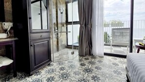 Een moderne hotelkamer met een douchecabine van glas, een balkon met uitzicht en een vloer met een patroon.