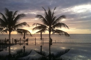 A beach scene with palm trees and a sunset over the ocean. - The Palmy Phu Quoc Resort & Spa (Phu Quoc Island)
