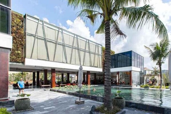 A modern building with a pool area, palm trees, and outdoor seating. - The Palmy Phu Quoc Resort & Spa (Phu Quoc Island)