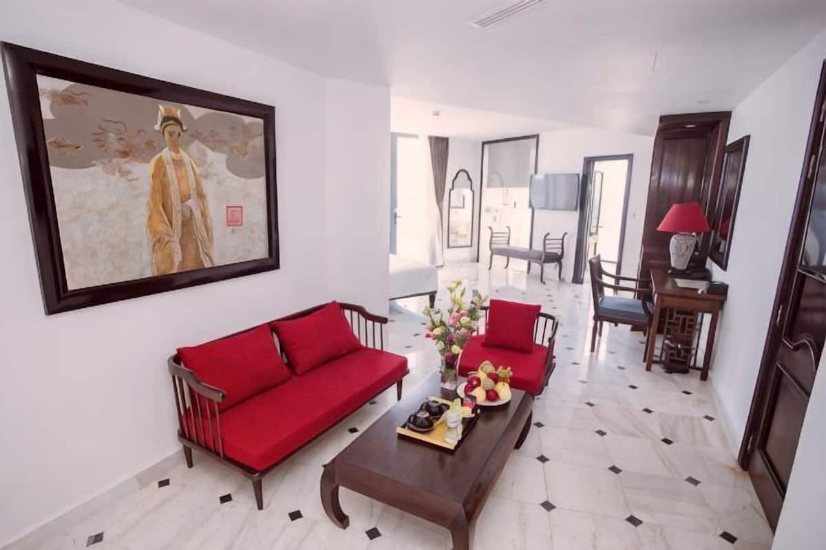 Ein Wohnzimmer mit einem roten Sofa, einem Couchtisch mit Blumen und einem Gemälde an der Wand.