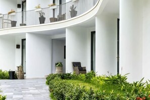 Un bâtiment moderne doté d’un balcon incurvé, de plantes en pot et d’un sol à carreaux.