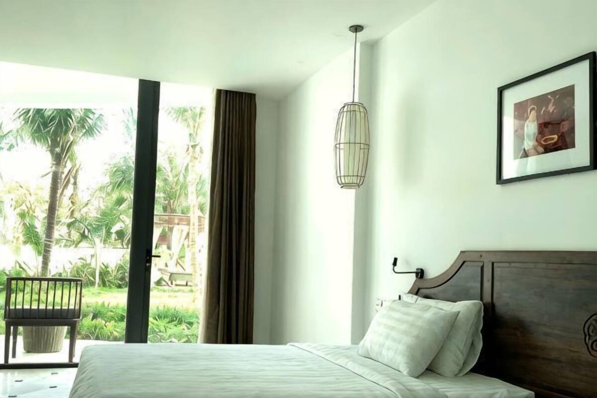 Ein Schlafzimmer mit Bett, Stuhl, einer Hängelampe und einem gerahmten Bild an der Wand.