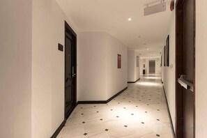 A hotel hallway with a tiled floor, doors, and framed pictures on the walls. - The Palmy Phu Quoc Resort & Spa (Phu Quoc Island)