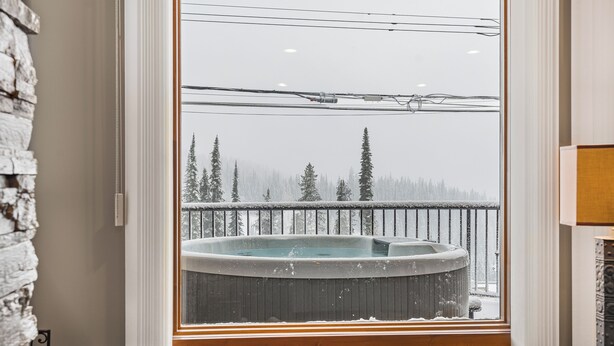 Ein Whirlpool auf einem Balkon mit Blick auf einen verschneiten Wald.