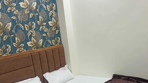A single bed with a brown headboard, white bedding, and a dark brown blanket. - OM TRINETRA PALACE (Ujjain)