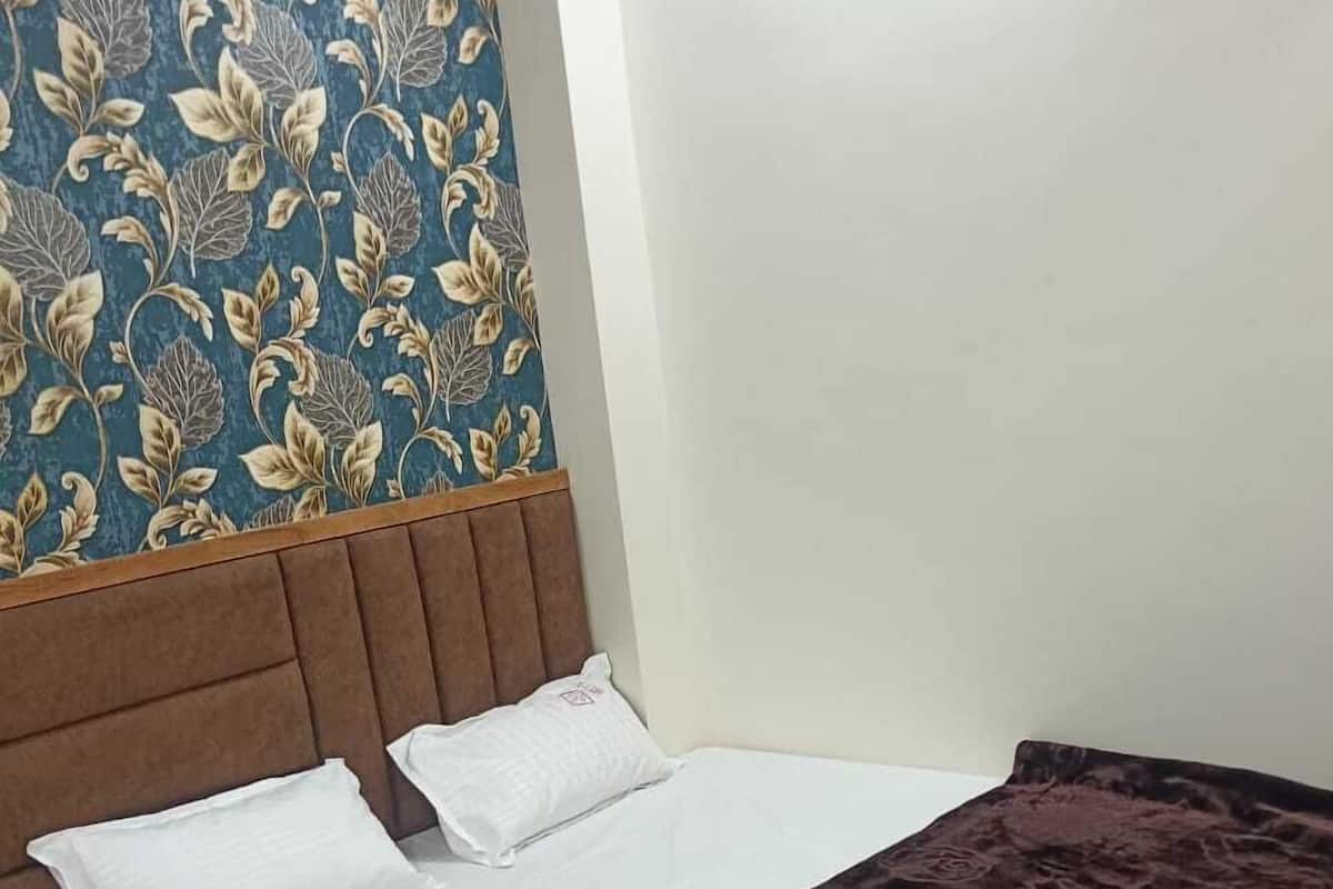 A single bed with a brown headboard, white bedding, and a dark brown blanket.
