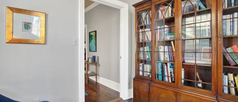 A room with a wooden bookcase, a framed picture on the wall, and two blue sofas.