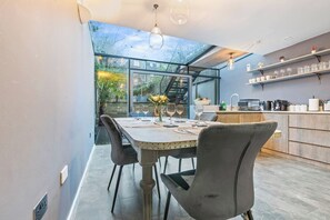 A modern kitchen with a large island, built-in appliances, and a view through a glass wall. - Modern | Spacious | Luxury 4 Bed in Camden Town (Greater London)