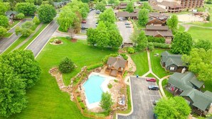 An aerial view of a resort with a swimming pool, multiple buildings, and a parking area surrounded by lush greenery. - Golf Lover's Retreat – Spacious Home in Old Kinderhook (Camdenton)
