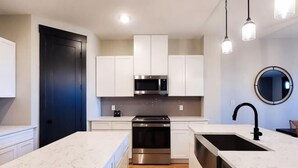 A modern kitchen with white cabinetry, stainless steel appliances, and a marble countertop. - Loop, New Luxurious Large 3BR, Sleeps 9 + Parking (Collin County)