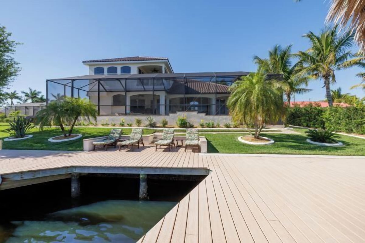 A modern house with a pool, outdoor seating, and palm trees.