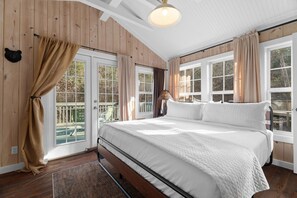 Une chambre à coucher avec un grand lit, des murs en bois et de nombreuses fenêtres.