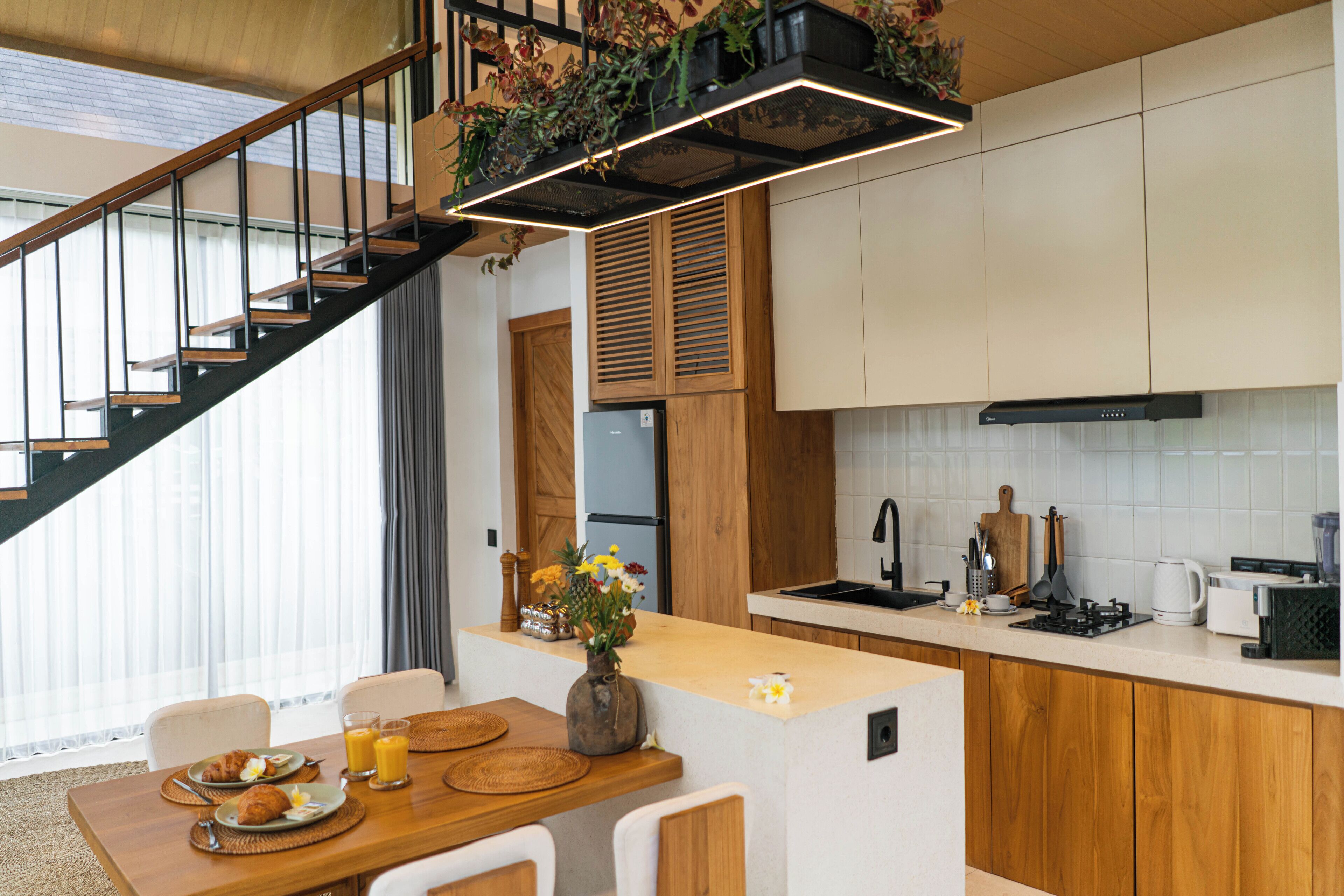 Eine moderne Küche mit Holzausstattung, einem eingebauten Herd und einem Essbereich mit Holztisch und -stühlen.