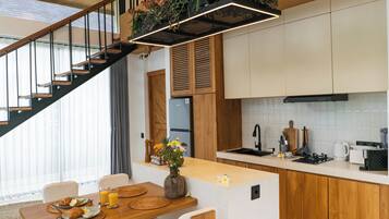 Eine moderne Küche mit Holzausstattung, einem eingebauten Herd und einem Essbereich mit Holztisch und -stühlen.